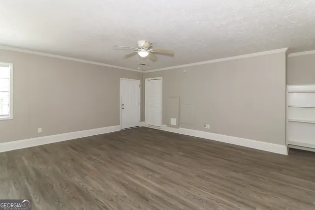 an empty room with wooden floor and fan