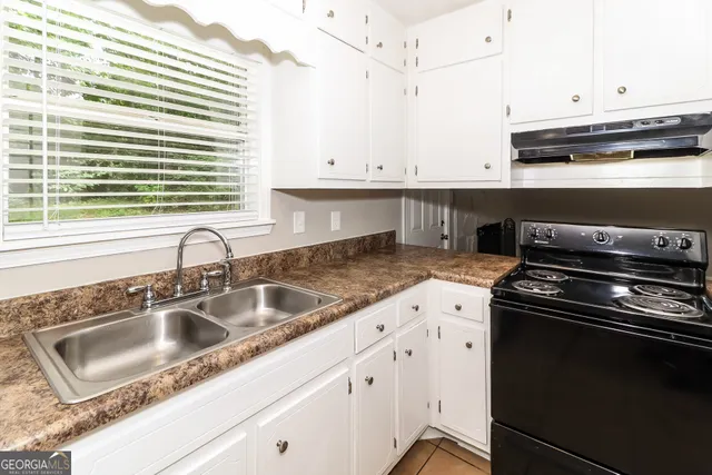 a kitchen with granite countertop a sink stove and cabinets