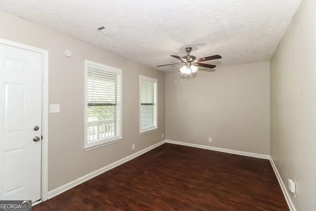 an view of an empty room with wooden floor and a window