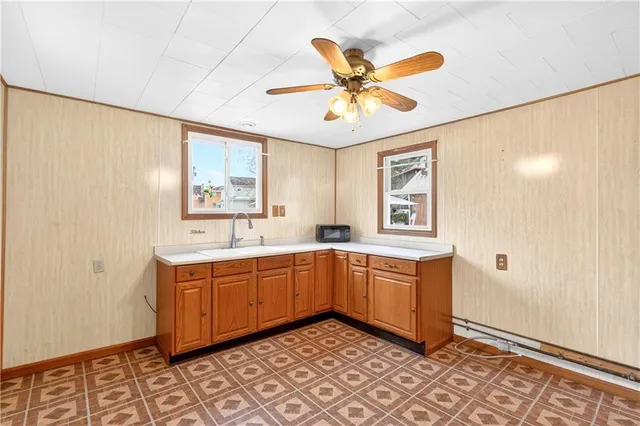 a utility room with stainless steel appliances granite countertop a stove a sink and a refrigerator with wooden floors