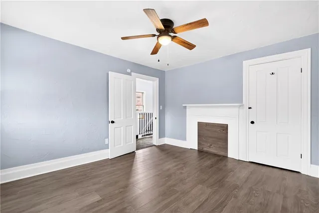 an empty room with wooden floor ceiling fan and windows
