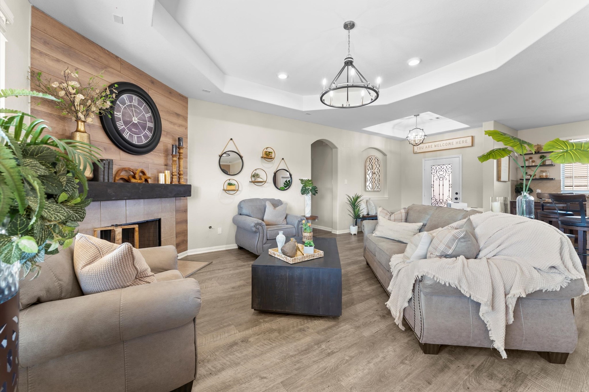 9729 Hidalgo Street Conroe, TX 77303 - Photo 11 of 38 Cozy living area features fireplace with decorative wood accent wall, modern chandelier. The space is bright and airy creating a warm, welcoming atmosphere.