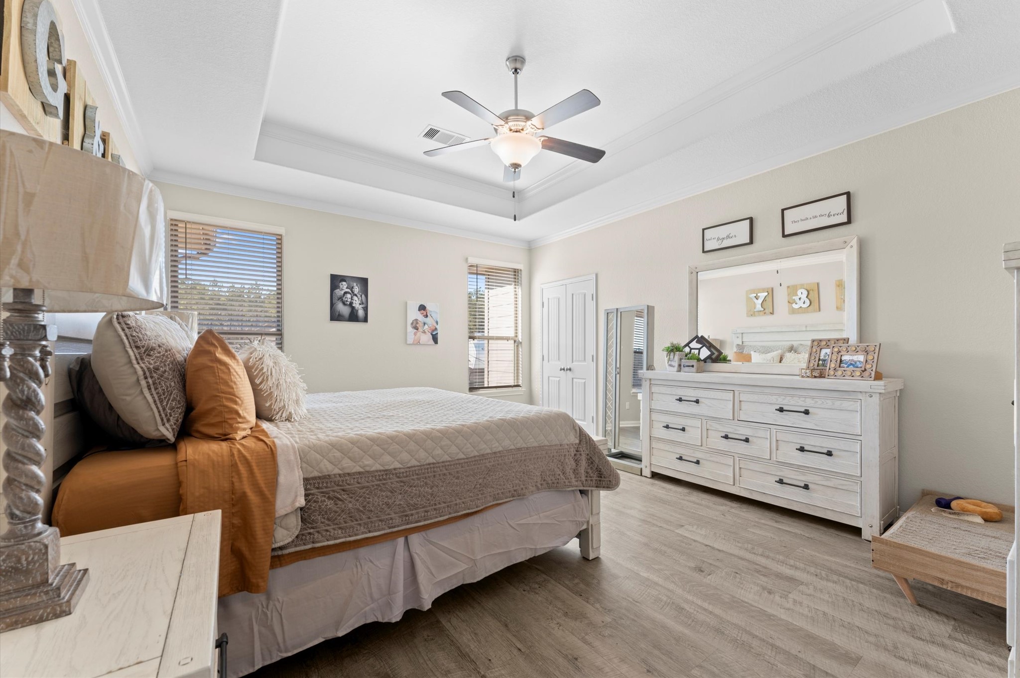 9729 Hidalgo Street Conroe, TX 77303 - Photo 24 of 38 Spacious Primary bedroom with natural light, featuring a tray ceiling and ceiling fan. It has a warm and inviting atmosphere.