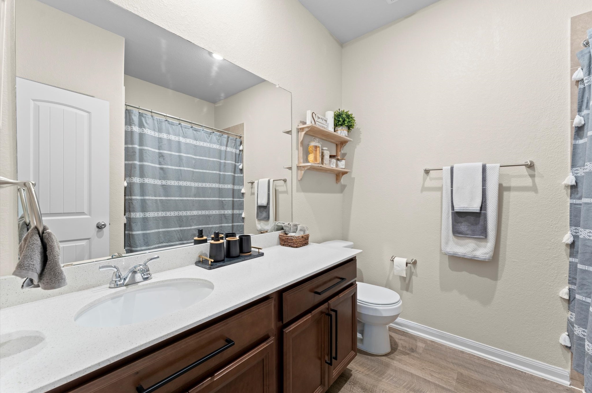 9729 Hidalgo Street Conroe, TX 77303 - Photo 25 of 38 The hall bathroom which features a modern design with a spacious vanity, sleek countertop, and ample storage. It includes a shower/tub combo with a neutral color palette. Floating shelves add a touch of elegance and practicality.