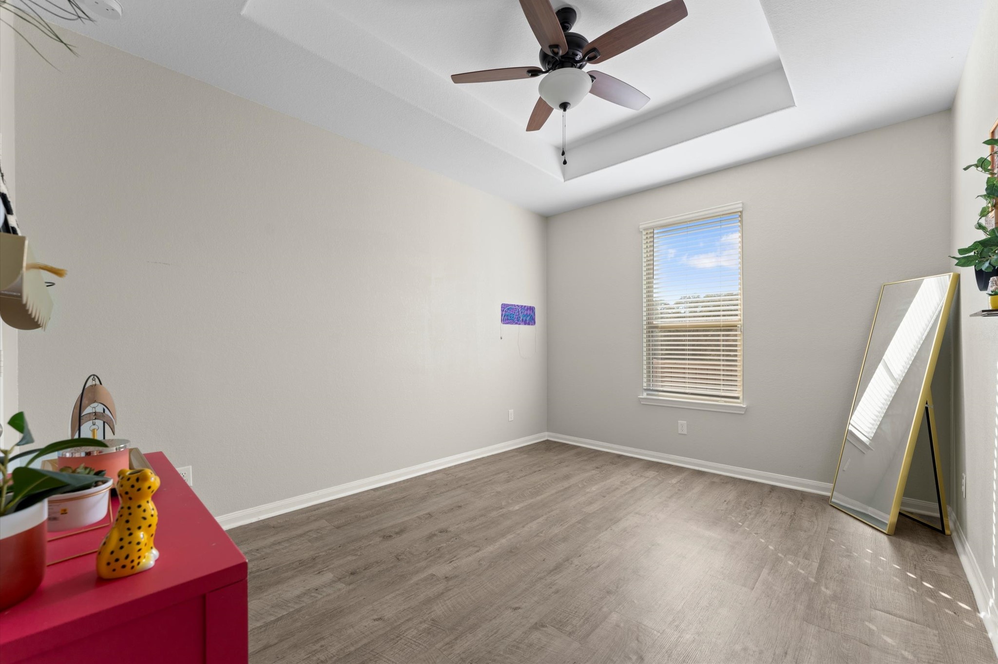 9729 Hidalgo Street Conroe, TX 77303 - Photo 28 of 38 Bright space with light-color walls and wood-look vinyl flooring. It has a tray ceiling, ceiling fan, a window with blinds offering a modern and airy feel.