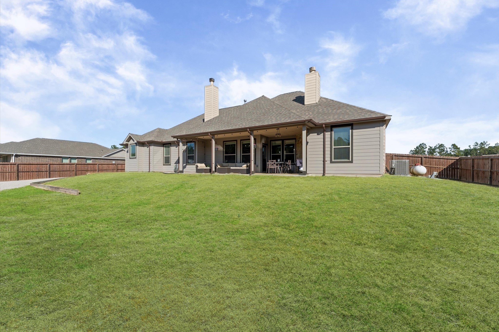 9729 Hidalgo Street Conroe, TX 77303 - Photo 32 of 38 Spacious backyard ideal for outdoor activities. The house features a covered patio with seating, perfect for relaxation and entertaining. The property is bordered by a wooden fence, providing privacy.