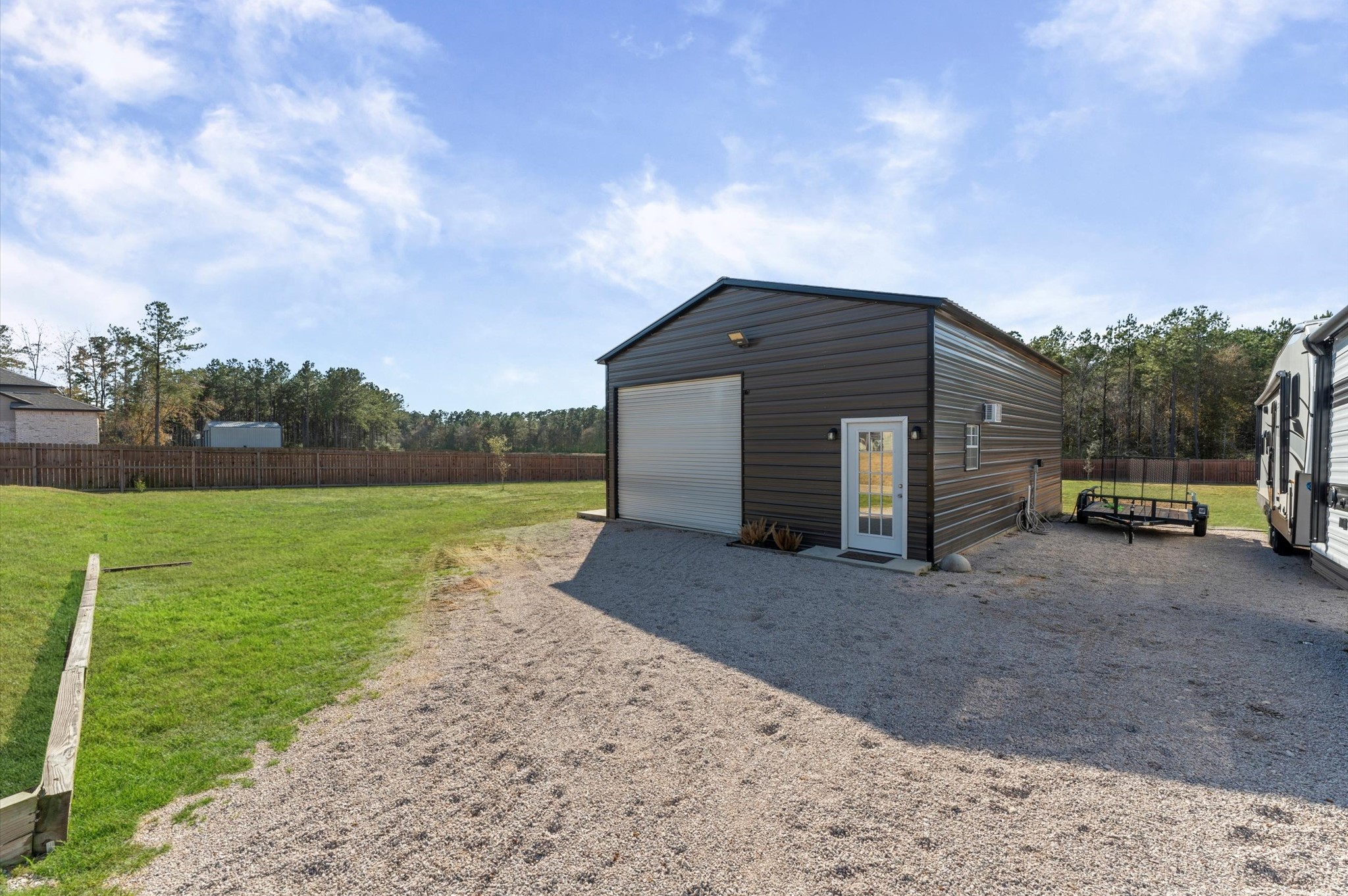 9729 Hidalgo Street Conroe, TX 77303 - Photo 34 of 38 Modern, metal building featuring a large garage door and side entry door. Perfect for storage or a workshop and includes an office. Behind the fenced perimeter, offering privacy and utility.