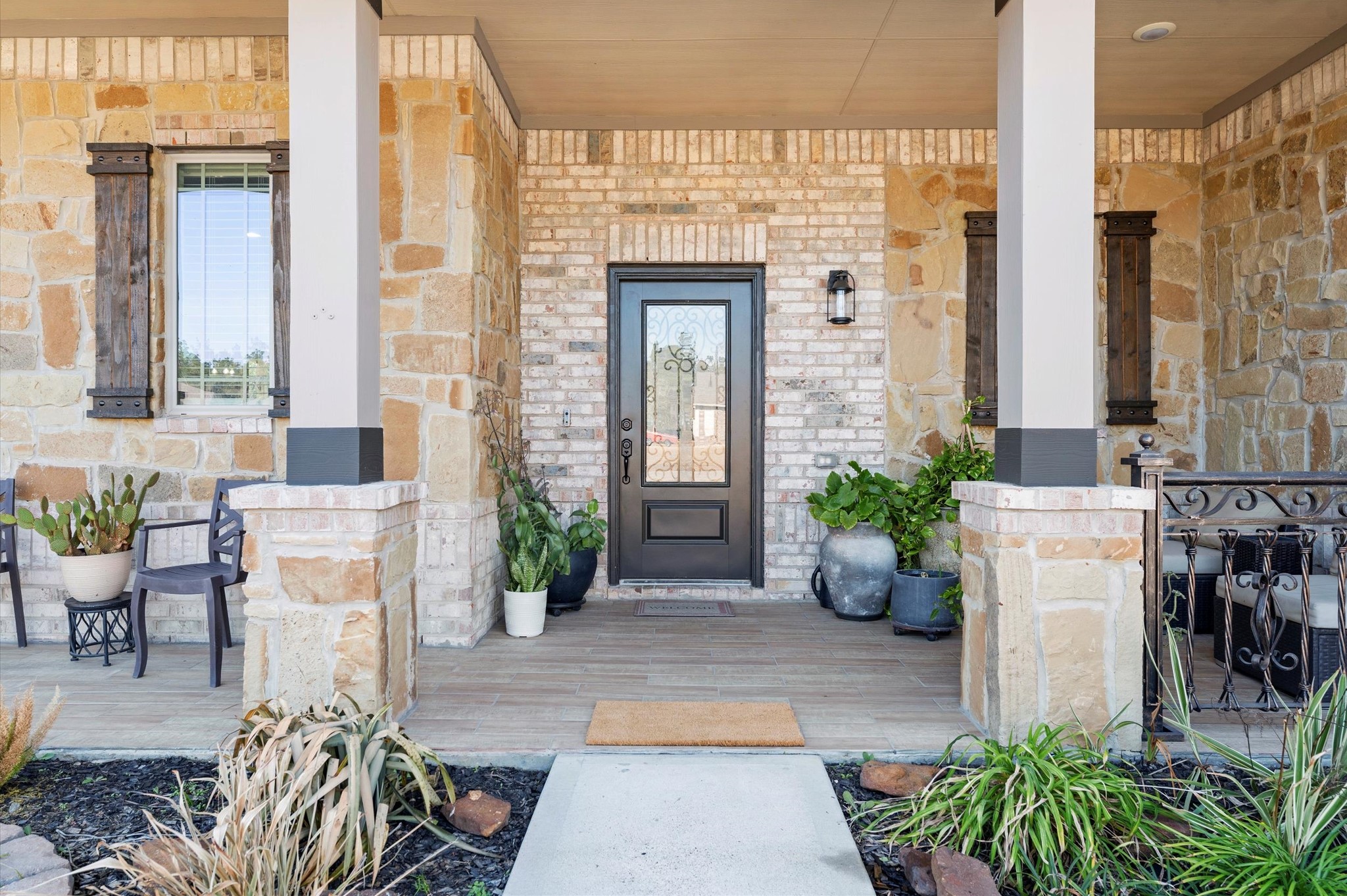 9729 Hidalgo Street Conroe, TX 77303 - Photo 6 of 38 Charming front entrance with a blend of stone and brickwork. It features a welcoming decorative glass front door and rustic wooden shutters. The porch is recently tiled and has stylish columns providing a warm and inviting entryway.
