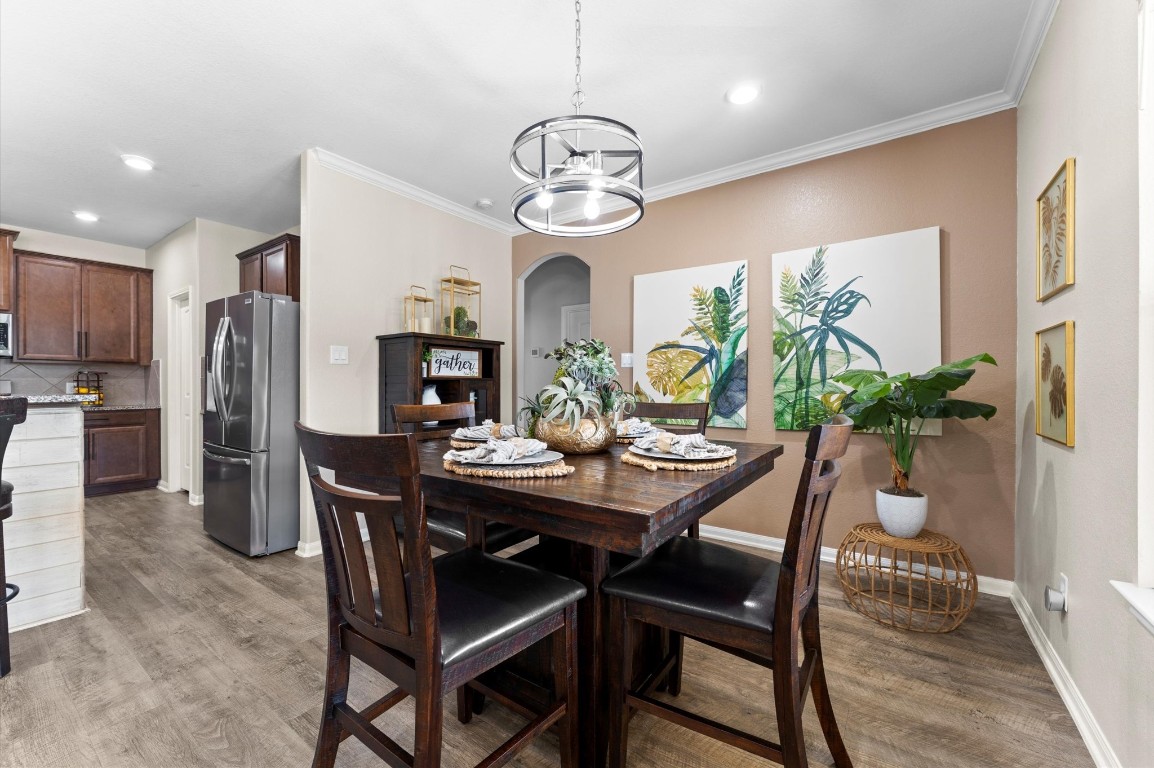 9729 Hidalgo Street Conroe, TX 77303 - Photo 9 of 38 This inviting dining area opens into a kitchen with sleek stainless steel appliances and rich cabinetry, all set against warm-toned walls and flooring.