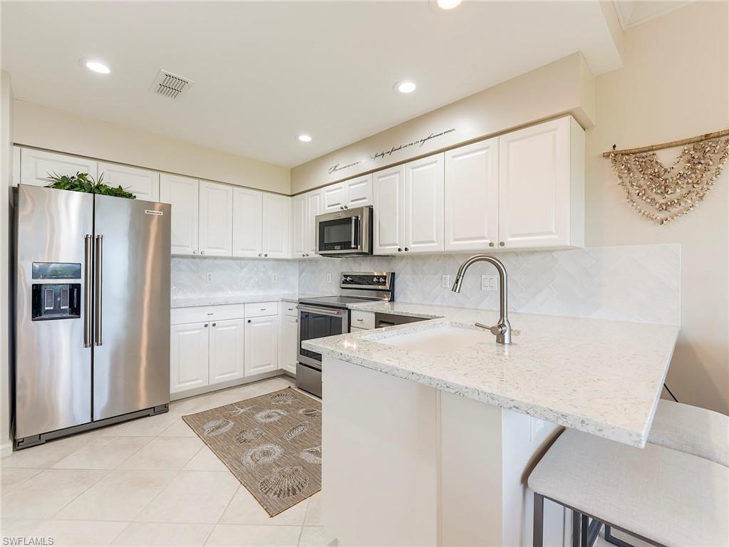 23011 Rosedale Drive, Unit 101 Estero, FL 34135 - Photo 12 of 34 a kitchen with stainless steel appliances granite countertop a refrigerator sink and stove