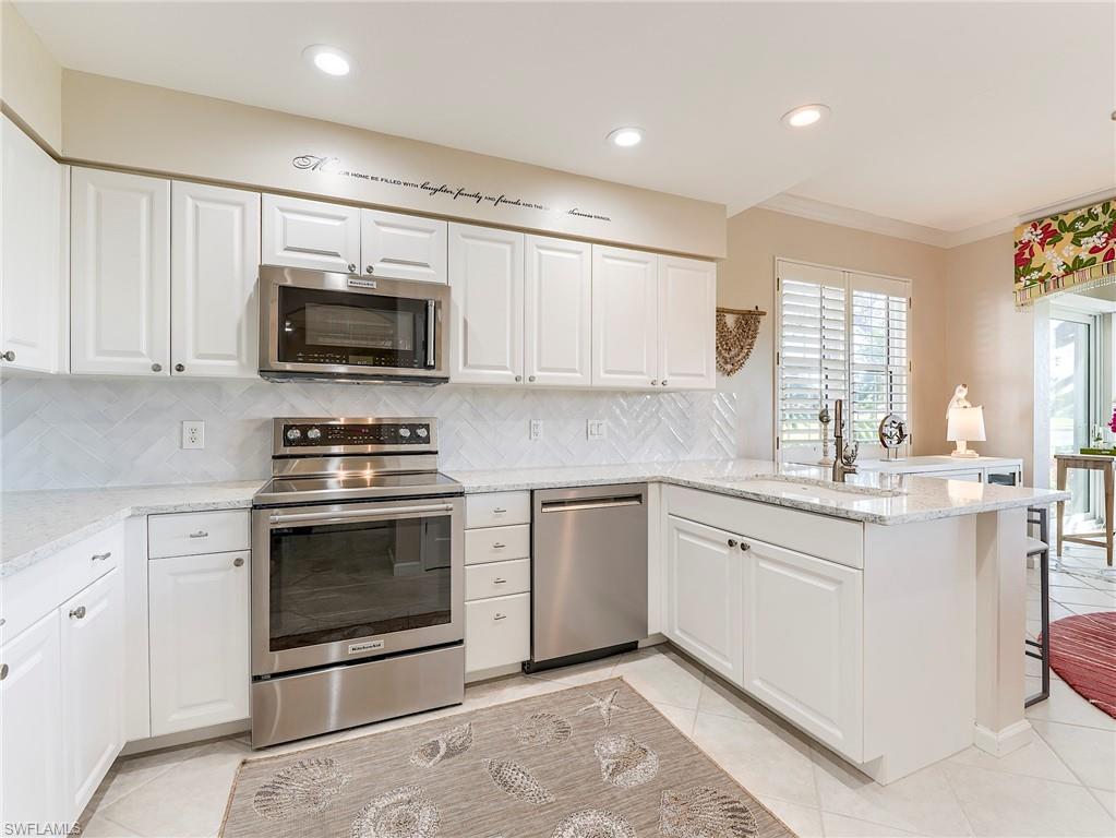 23011 Rosedale Drive, Unit 101 Estero, FL 34135 - Photo 13 of 34 a kitchen with granite countertop a stove a sink and a microwave