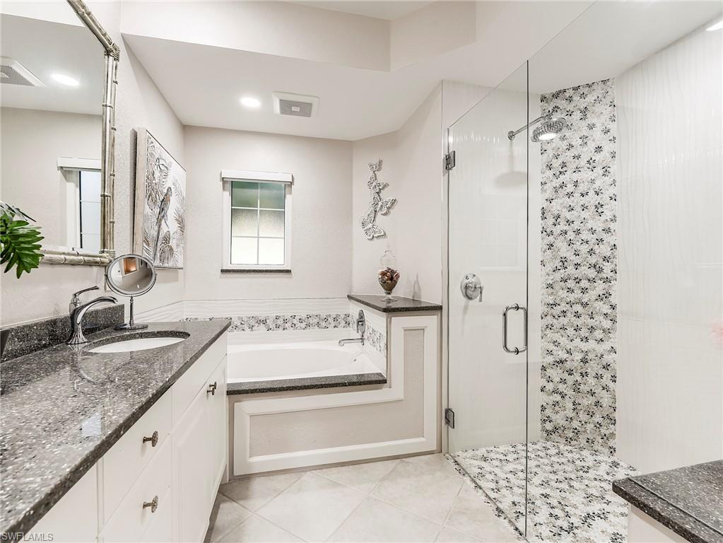 23011 Rosedale Drive, Unit 101 Estero, FL 34135 - Photo 24 of 34 a bathroom with a granite countertop sink a mirror and a shower