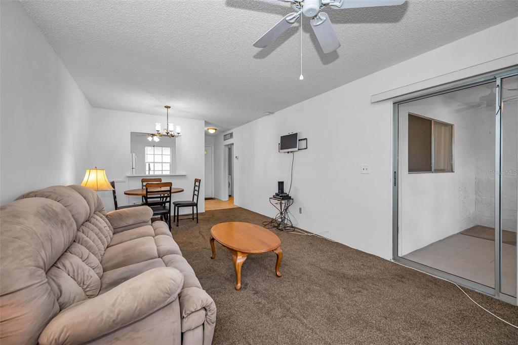 3116 Highlands Boulevard, Unit 3116 Palm Harbor, FL 34684 - Photo 13 of 56 a living room with furniture a chandelier and a wooden floor