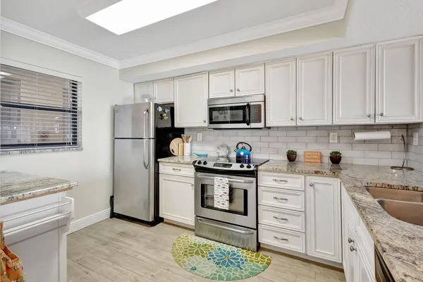 a kitchen with stainless steel appliances granite countertop a refrigerator stove a sink and a microwave