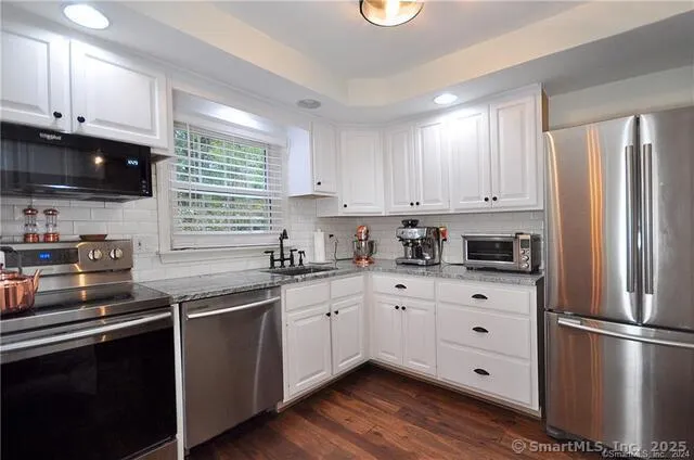 a kitchen with stainless steel appliances granite countertop a refrigerator sink and white cabinets