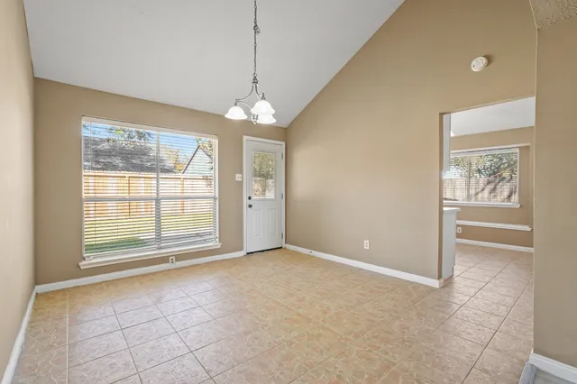an empty room with chandelier fan and windows