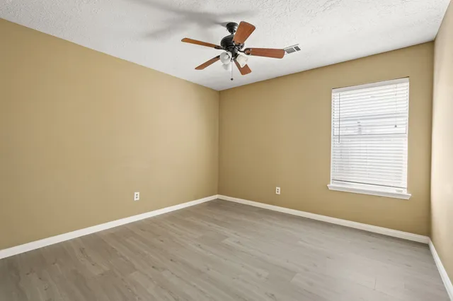 an empty room with a window and a ceiling fan
