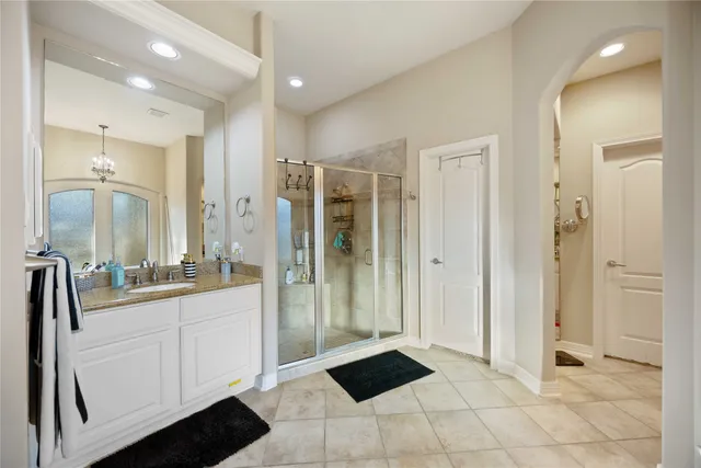 a large bathroom with a glass shower door a sink and a mirror
