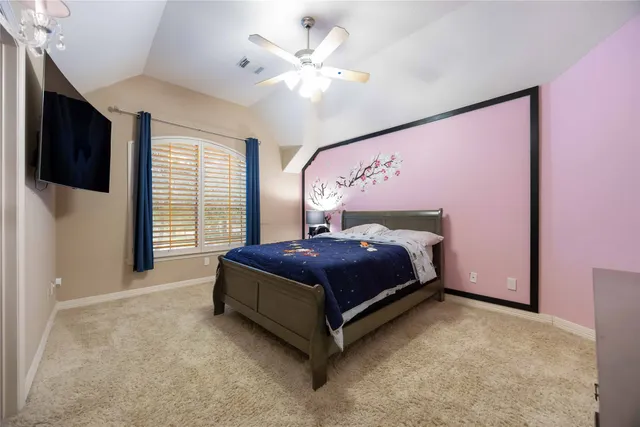 a spacious bedroom with a bed and a flat screen tv