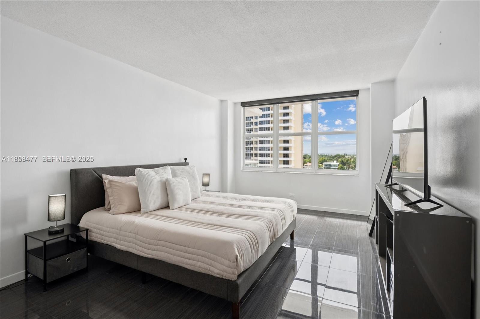 5601 Collins Avenue, Unit 820 Miami Beach, FL 33140 - Photo 9 of 23 a bedroom with a bed and a flat tv screen on a dresser