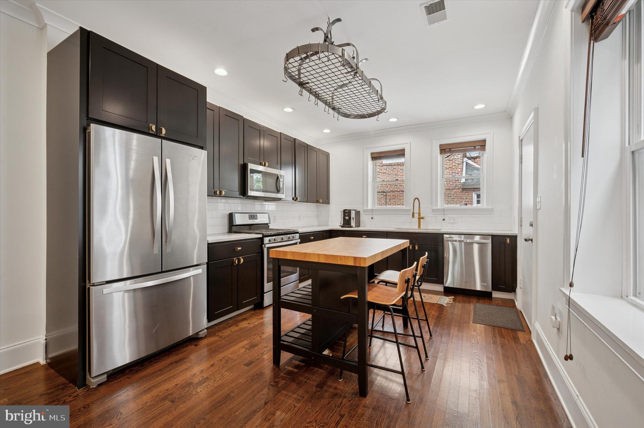 4935 Pine Street Philadelphia, PA 19143 - Photo 8 of 40 a kitchen with stainless steel appliances granite countertop a dining table chairs refrigerator and microwave