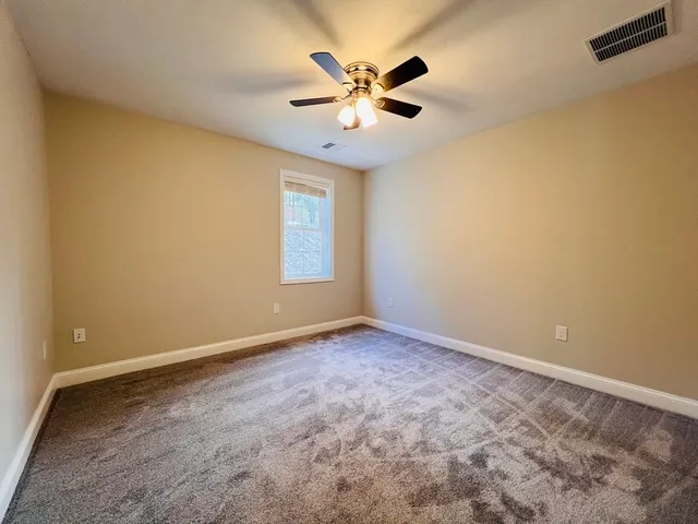 an empty room with windows and ceiling fan