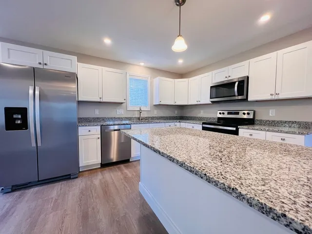 a kitchen with granite countertop a refrigerator a stove a sink a center island and cabinets