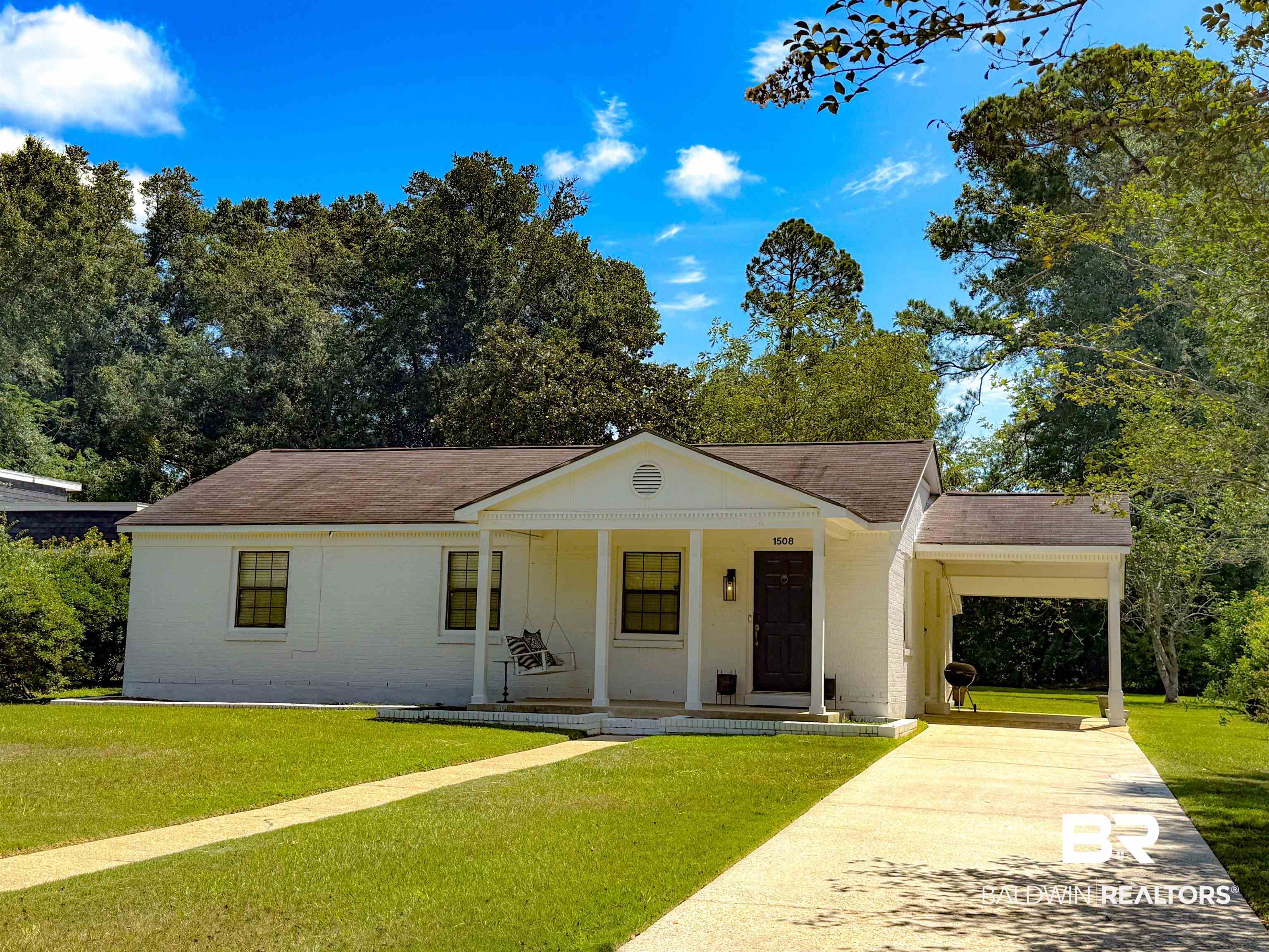 1508 Poplar Avenue Brewton, AL 36426 - Photo 1 of 22 View of front of house featuring a front yard, a porch, driveway, an attached carport, and a shingled roof