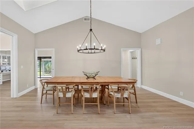 a kitchen with stainless steel appliances granite countertop a stove top oven a sink a dining table and chairs with wooden floor