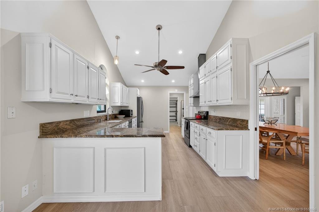 3211 Southeast Court Drive Stuart, FL 34997 - Photo 18 of 60 a kitchen with stainless steel appliances granite countertop a stove top oven a sink a dining table and chairs with wooden floor