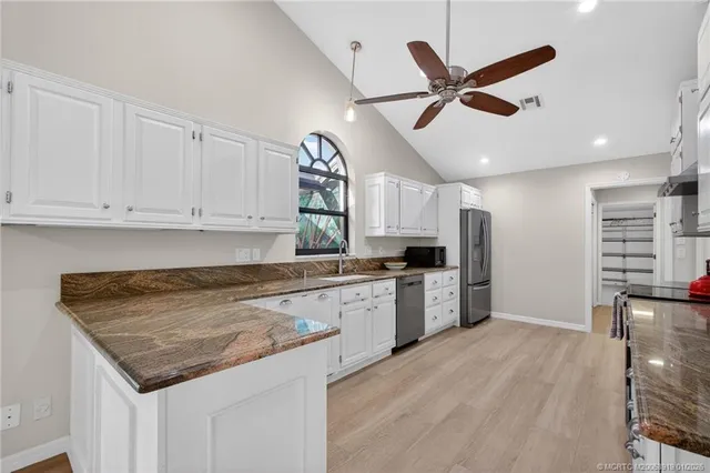 a kitchen with stainless steel appliances granite countertop a stove and white cabinets