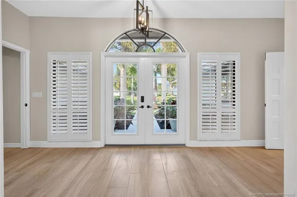a view of a dining room and livingroom with furniture wooden floor a chandelier