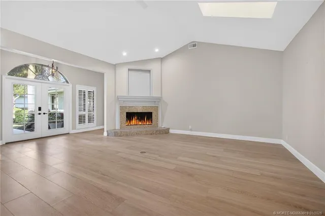 a view of an empty room with window and wooden floor