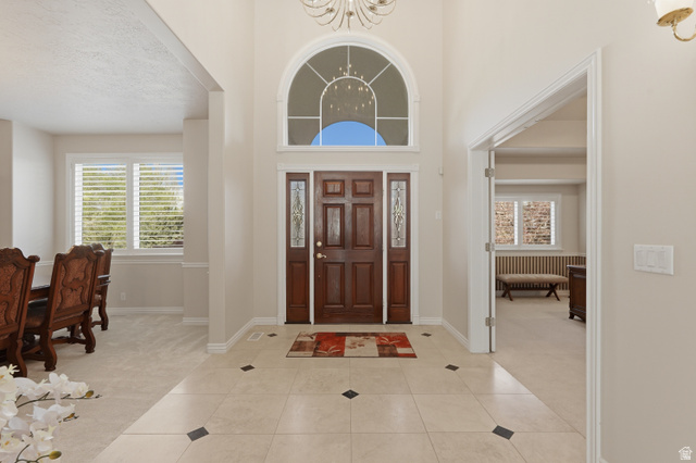 11943 Autumn Ridge Drive East Sandy, UT 84092 - Photo 3 of 59 Foyer entrance featuring light carpet, suspended lighting, a high ceiling, and light tile patterned floors
