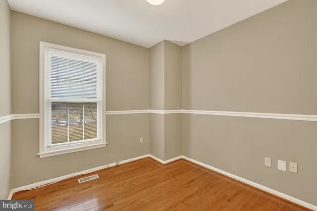 a view of an empty room with a window and hardwood floor