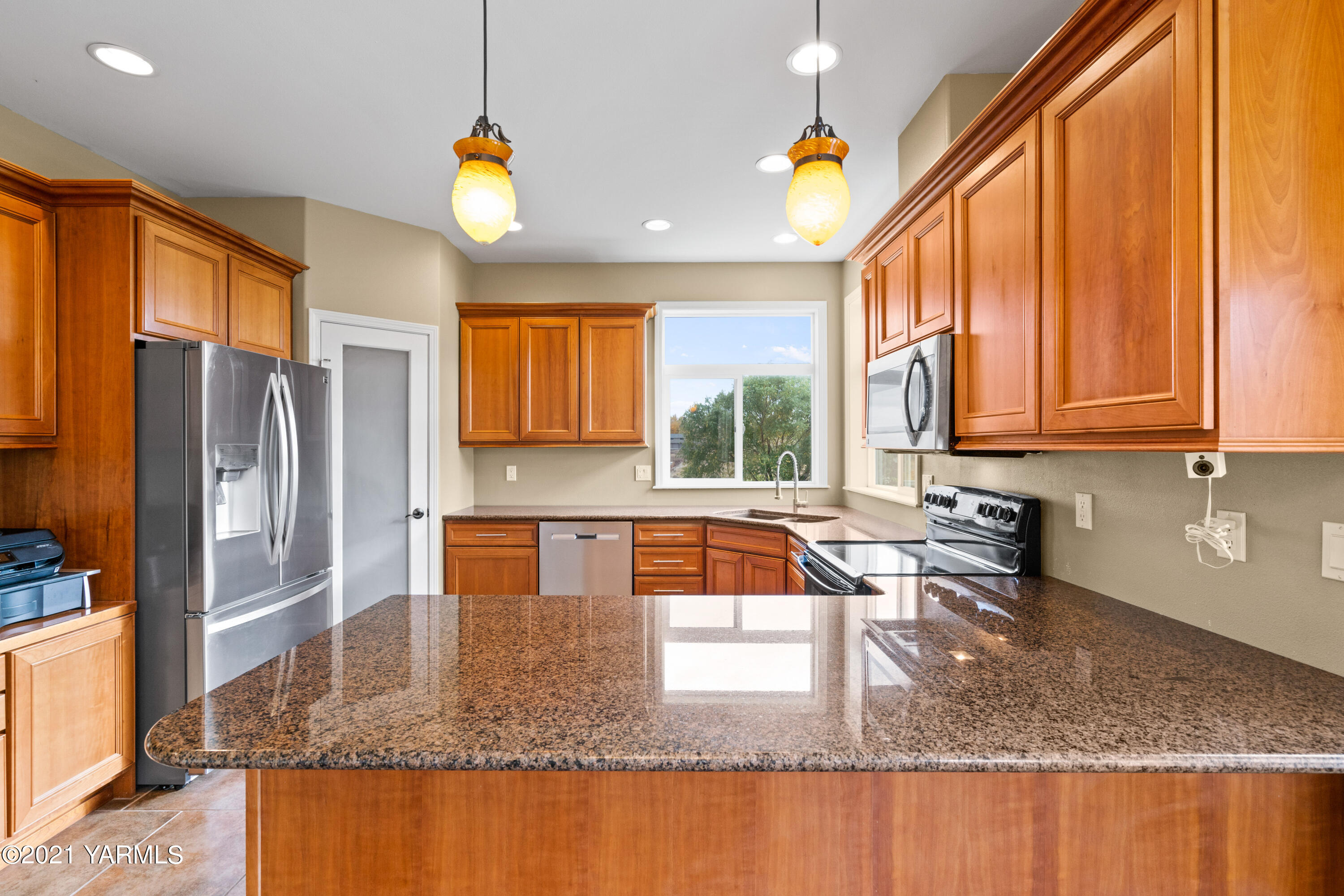 10807 Zier Road Yakima, WA 98908 - Photo 16 of 44 a kitchen with stainless steel appliances granite countertop a sink a stove a refrigerator a washer and dryer next to a window