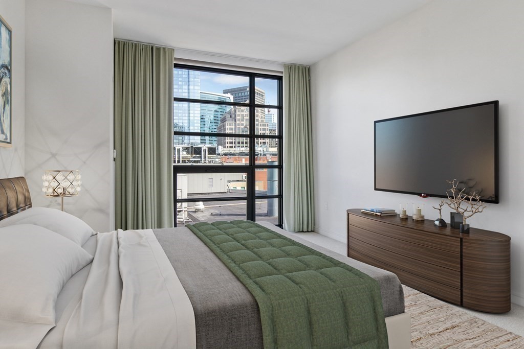 580 Washington Street, Unit 1207 Boston, MA 02111 - Photo 7 of 16 a bedroom with a bed and a flat screen tv