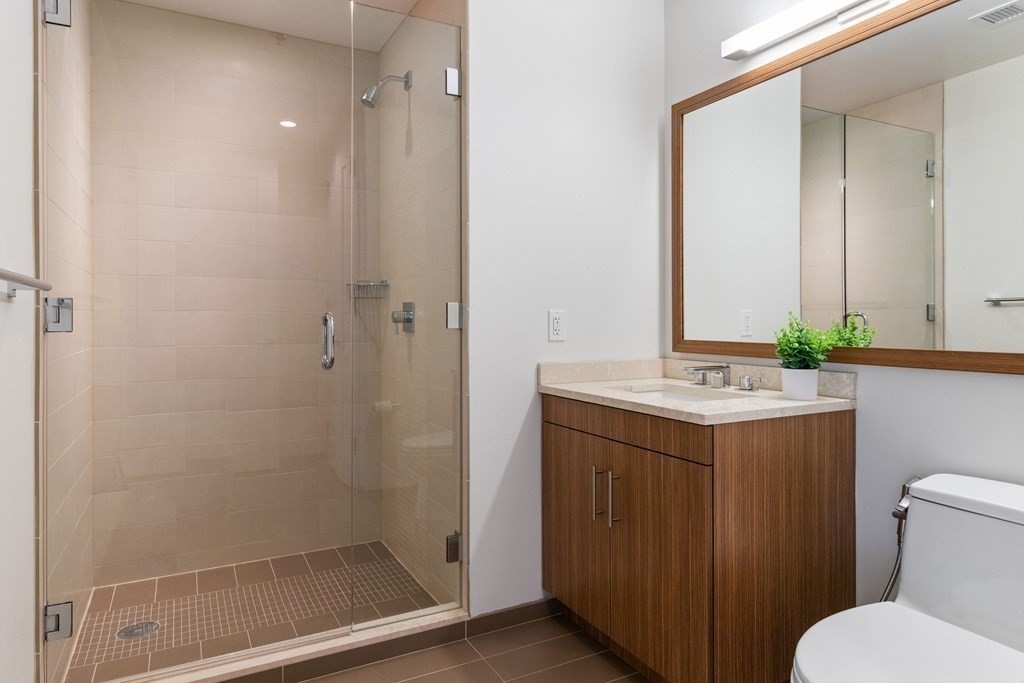 580 Washington Street, Unit 1207 Boston, MA 02111 - Photo 8 of 16 a bathroom with a granite countertop sink toilet and shower