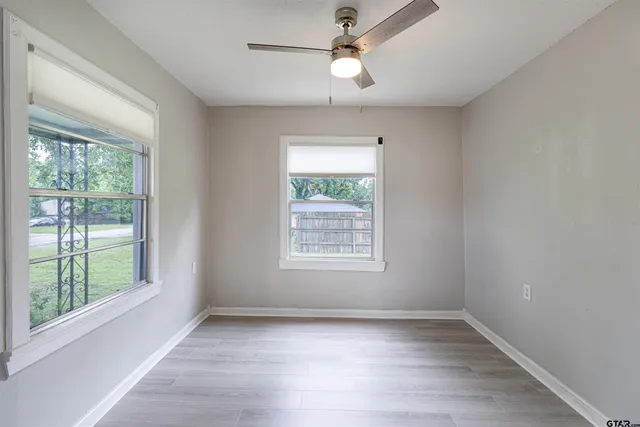 a view of an empty room with wooden floor and a window