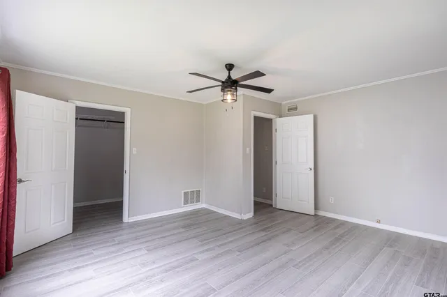 an empty room with wooden floor and ceiling fan