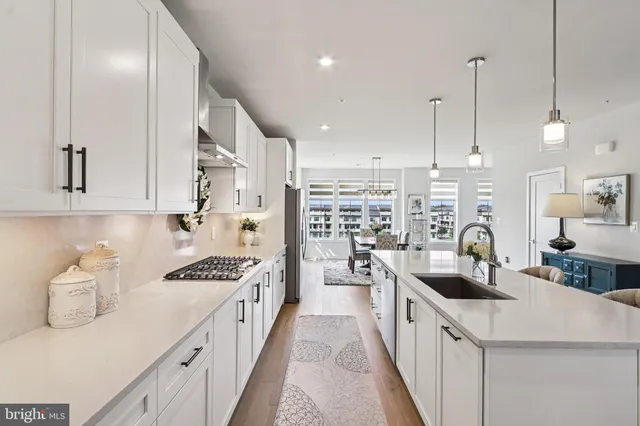 a kitchen with stainless steel appliances kitchen island granite countertop a sink a stove and a wooden floors