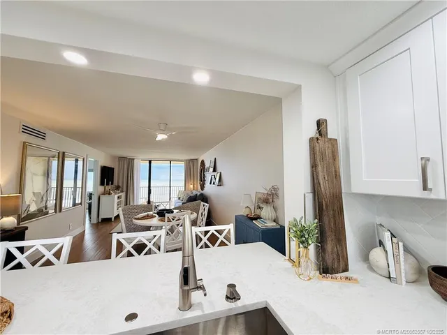 a living room with furniture a mirror and kitchen view