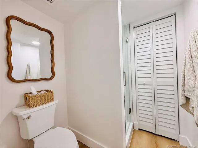 a bedroom with a bed a large window with dresser and mirror