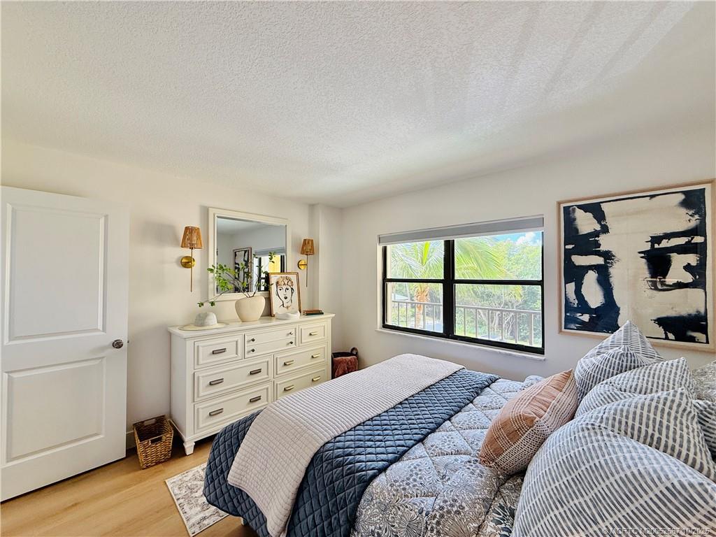 7370 South Ocean Drive, Unit 312 Jensen Beach, FL 34957 - Photo 56 of 67 a bedroom with a bed a large window with dresser and mirror