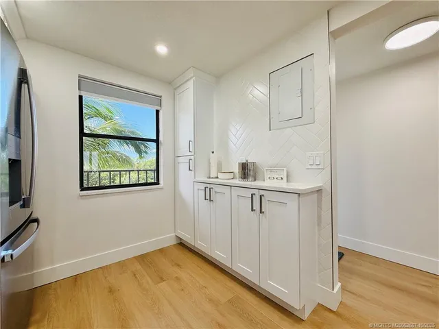 a kitchen with stainless steel appliances granite countertop a stove top oven a sink dishwasher and white cabinets with wooden floor