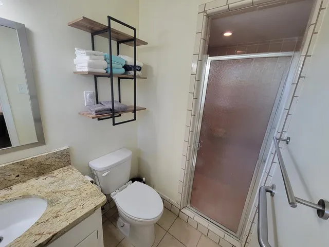 a bathroom with a granite countertop sink toilet and shower