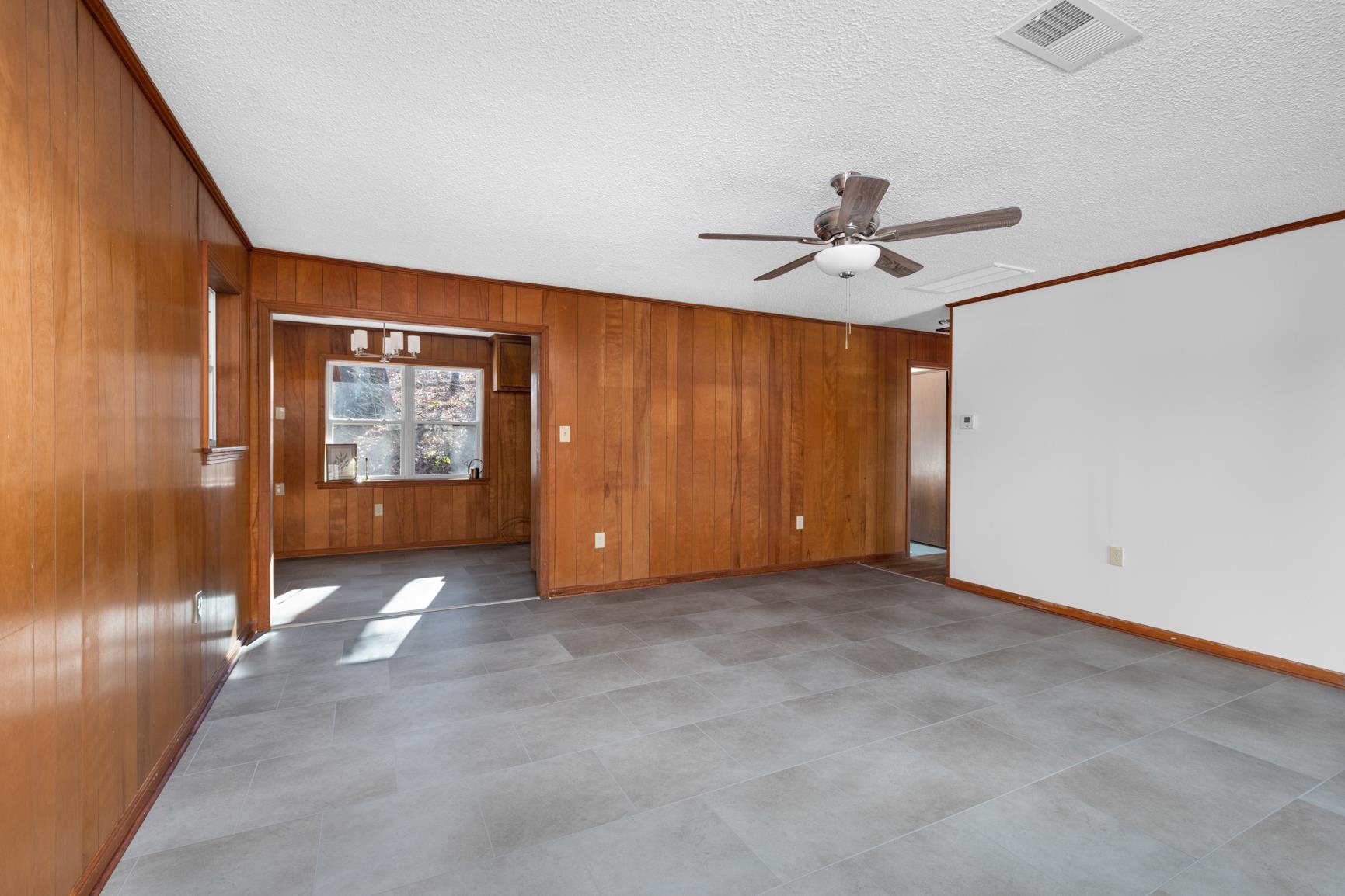 945 Gay Road Burlison, TN 38015 - Photo 11 of 27 Unfurnished room featuring ceiling fan, a textured ceiling, wood walls, and ornamental molding