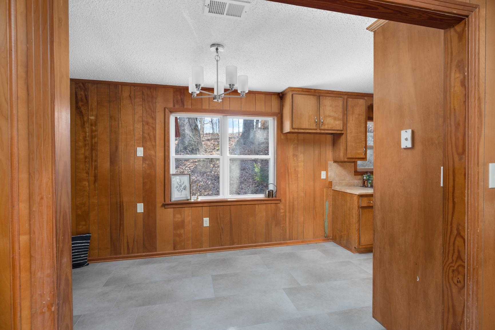 945 Gay Road Burlison, TN 38015 - Photo 12 of 27 Unfurnished dining area with a chandelier, a textured ceiling, wooden walls, and light flooring