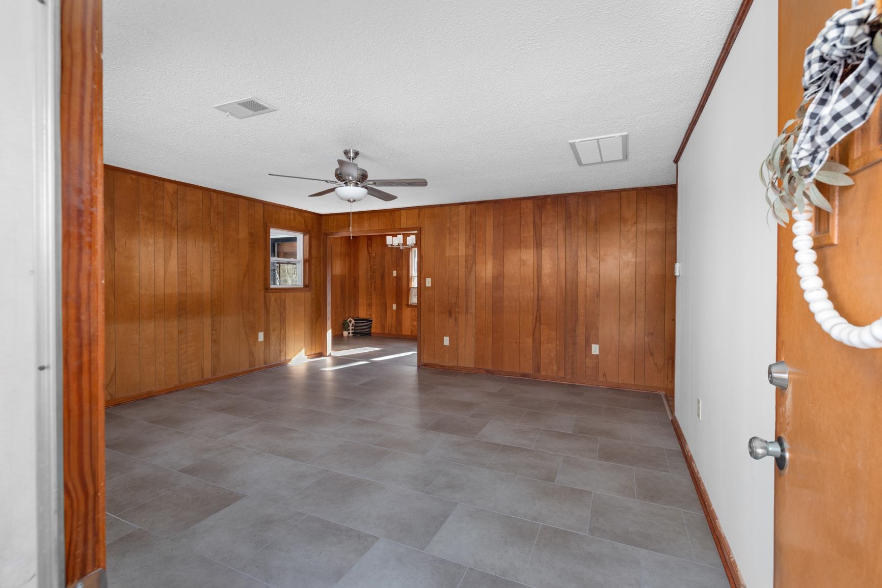 945 Gay Road Burlison, TN 38015 - Photo 8 of 27 Empty room featuring wooden walls, ceiling fan, and a textured ceiling