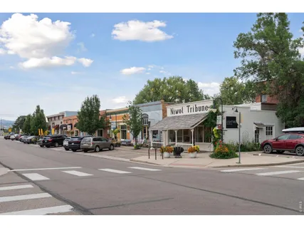 a view of road with card parked on side and retail shops